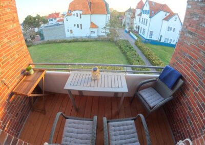 Balkon mit Stühle und Tischen, freier Blick auf eine Wiese