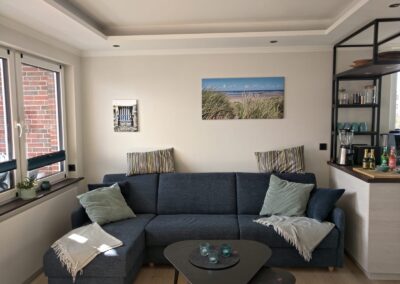 großes Sofa zum ausklappen, große Fenster, Bilder an der Wand und die offene Küche